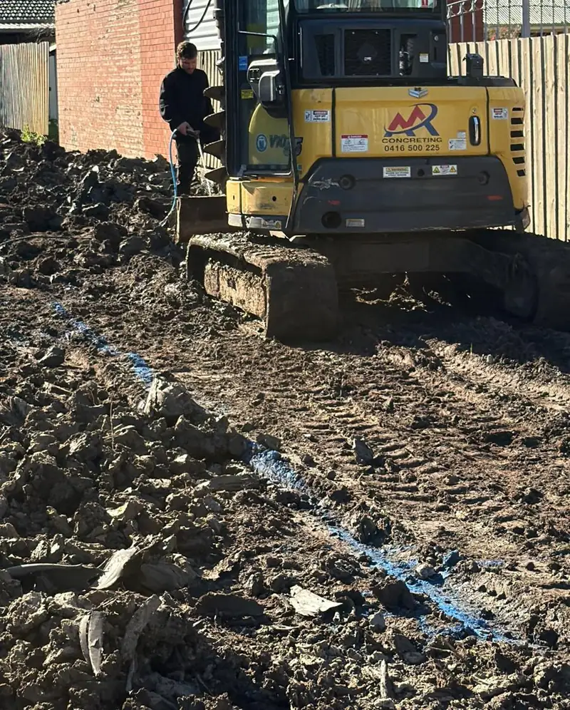 Excavator trenching along the marked set-out lines