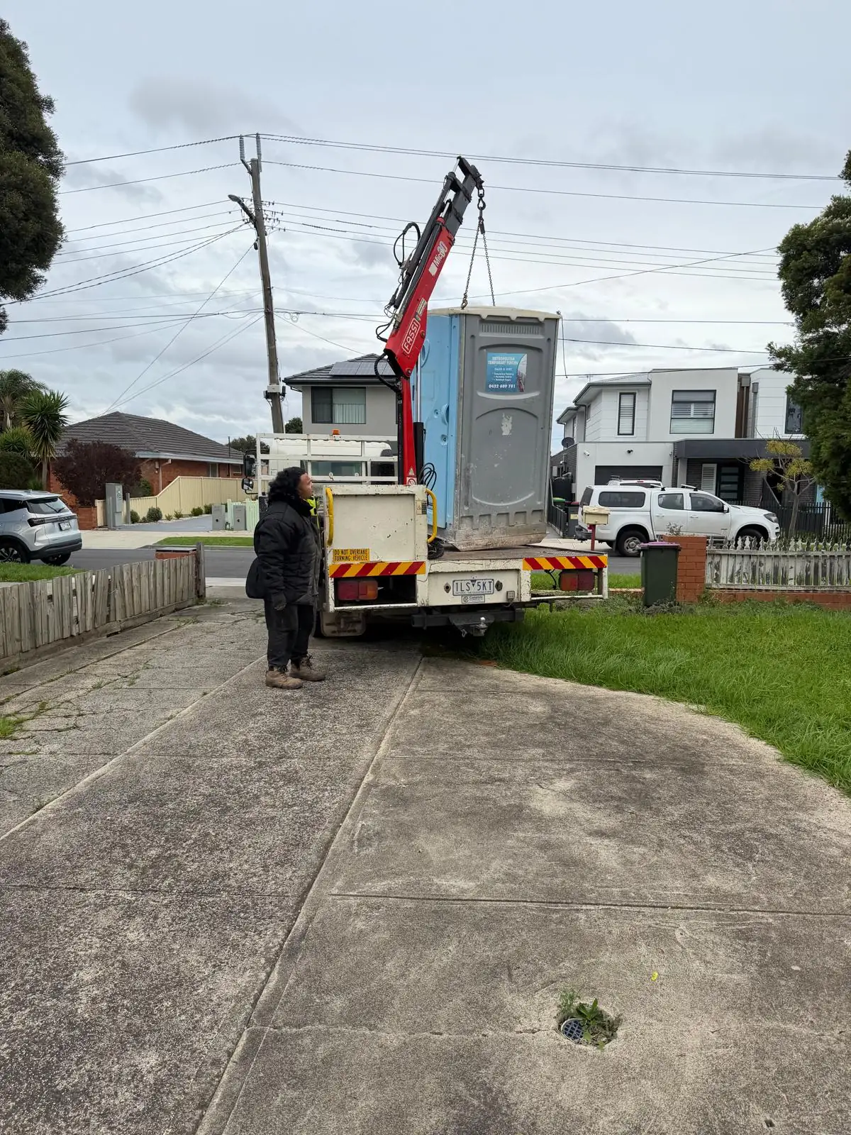 Site set-up: a portable site toilet being lifted into place from a truck crane