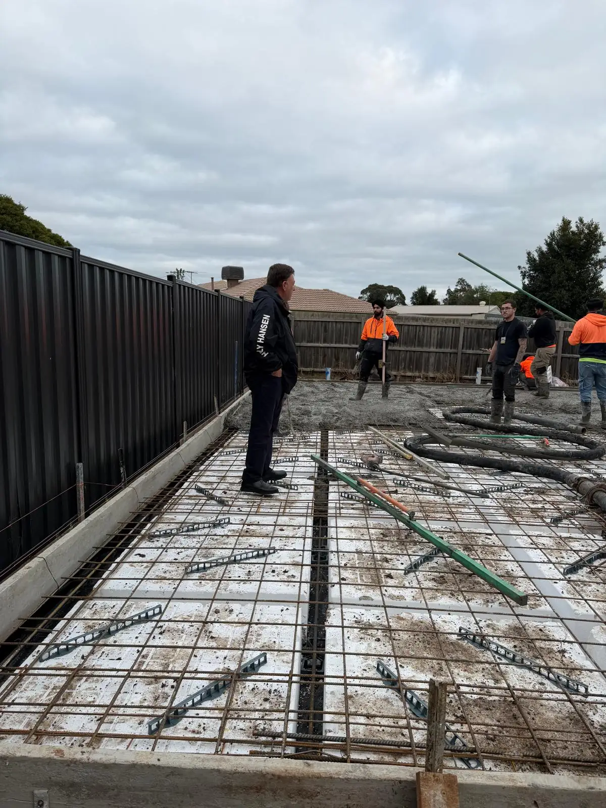 Site supervisor checking slab reinforcement while the crew prepares for the concrete pour