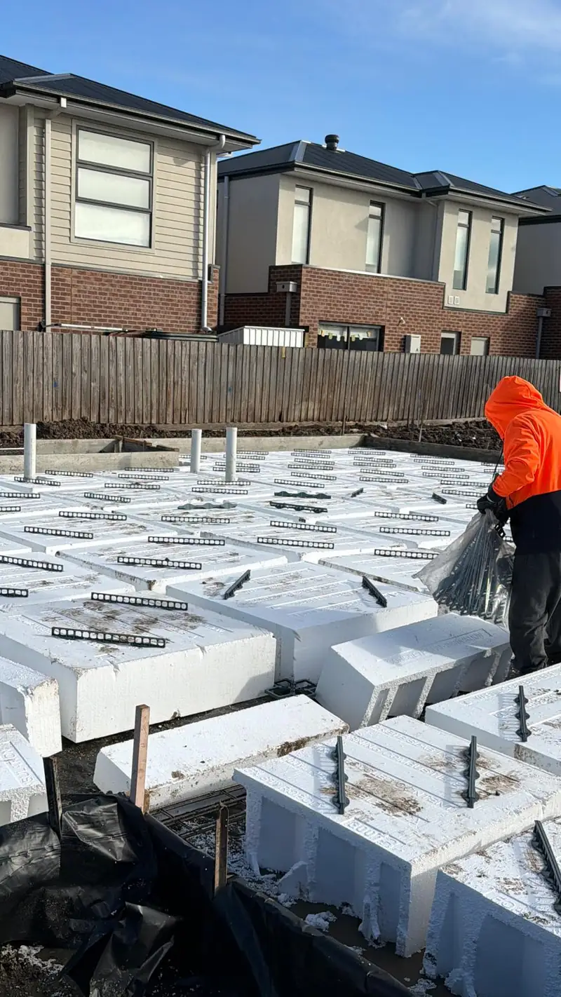 Waffle pods and reinforcement laid out for a townhouse slab, with neighbouring homes behind